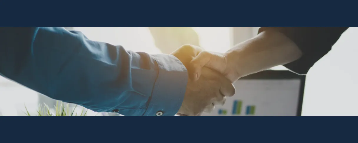 Two people shaking hands in front of a business chart